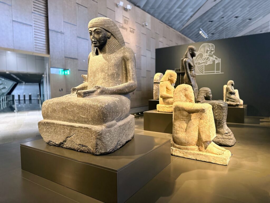 Stone statues of seated figures arranged on platforms at the Grand Egyptian Museum