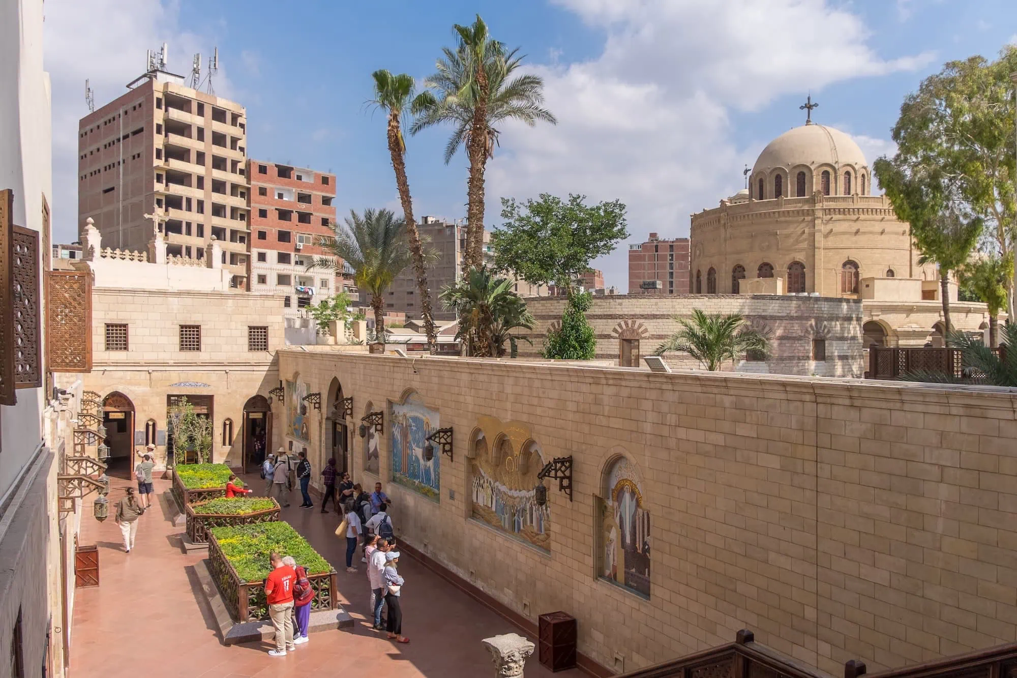Historic Coptic Cairo courtyard with stone buildings, dome, and Christian cross