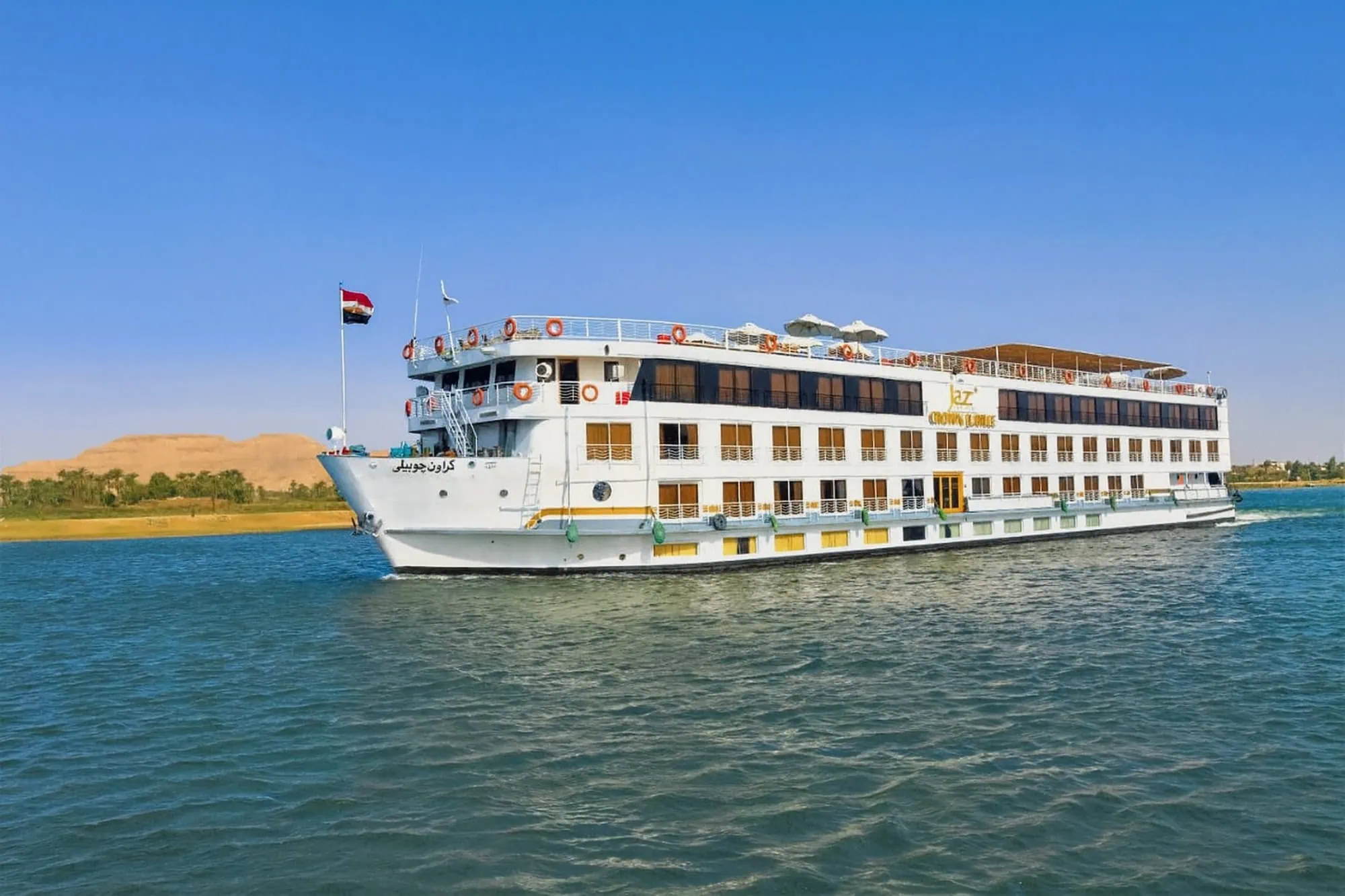 Crucero por el río Nilo con bandera egipcia navegando por aguas serenas