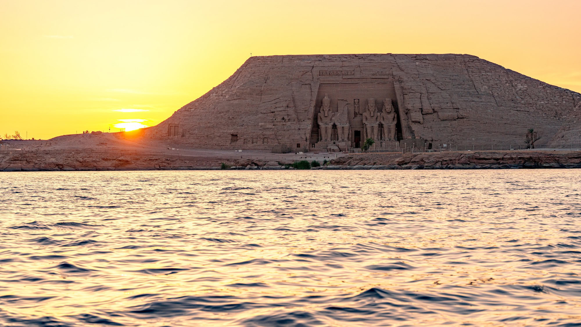 Abu Simbel Temple with colossal statues overlooking Lake Nasser at sunset in desert landscape