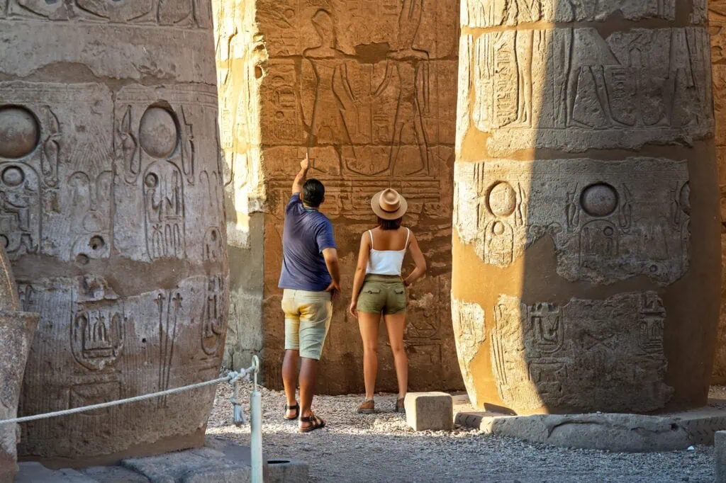 Tourist walking among the towering columns of Karnak Temple