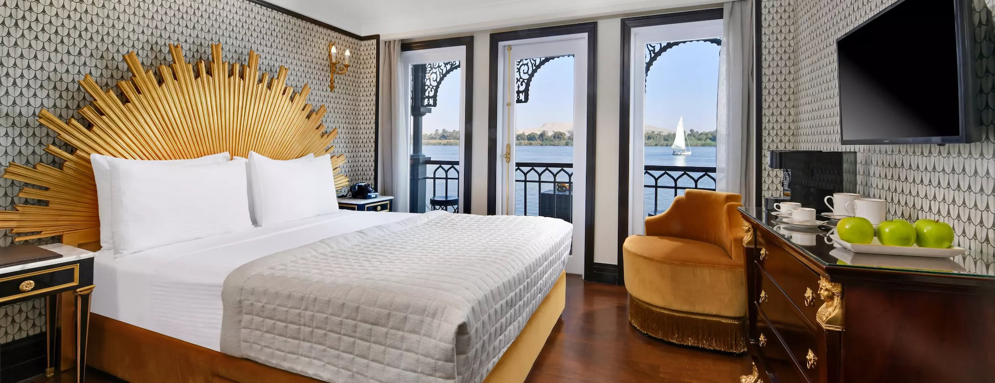 Luxurious cruise ship cabin with bed, balcony and Nile River view