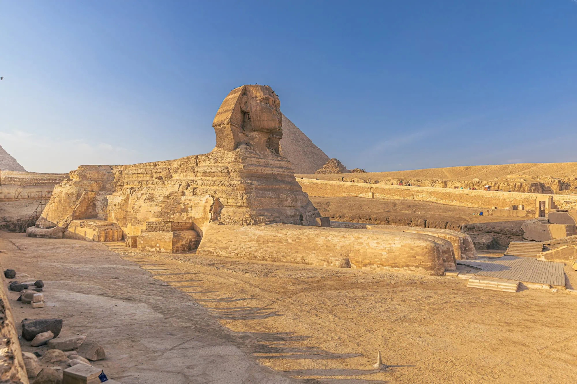 Great Sphinx of Giza with pyramid in background and tourists on walkways