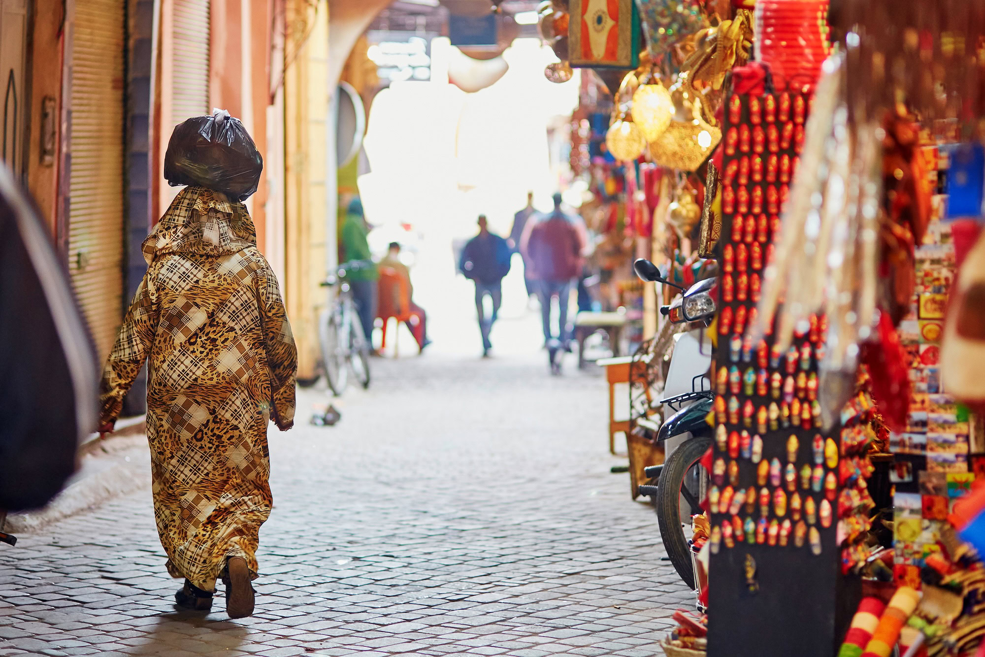 Souk marocchino tradizionale con bancarelle, tessuti colorati e lanterne
