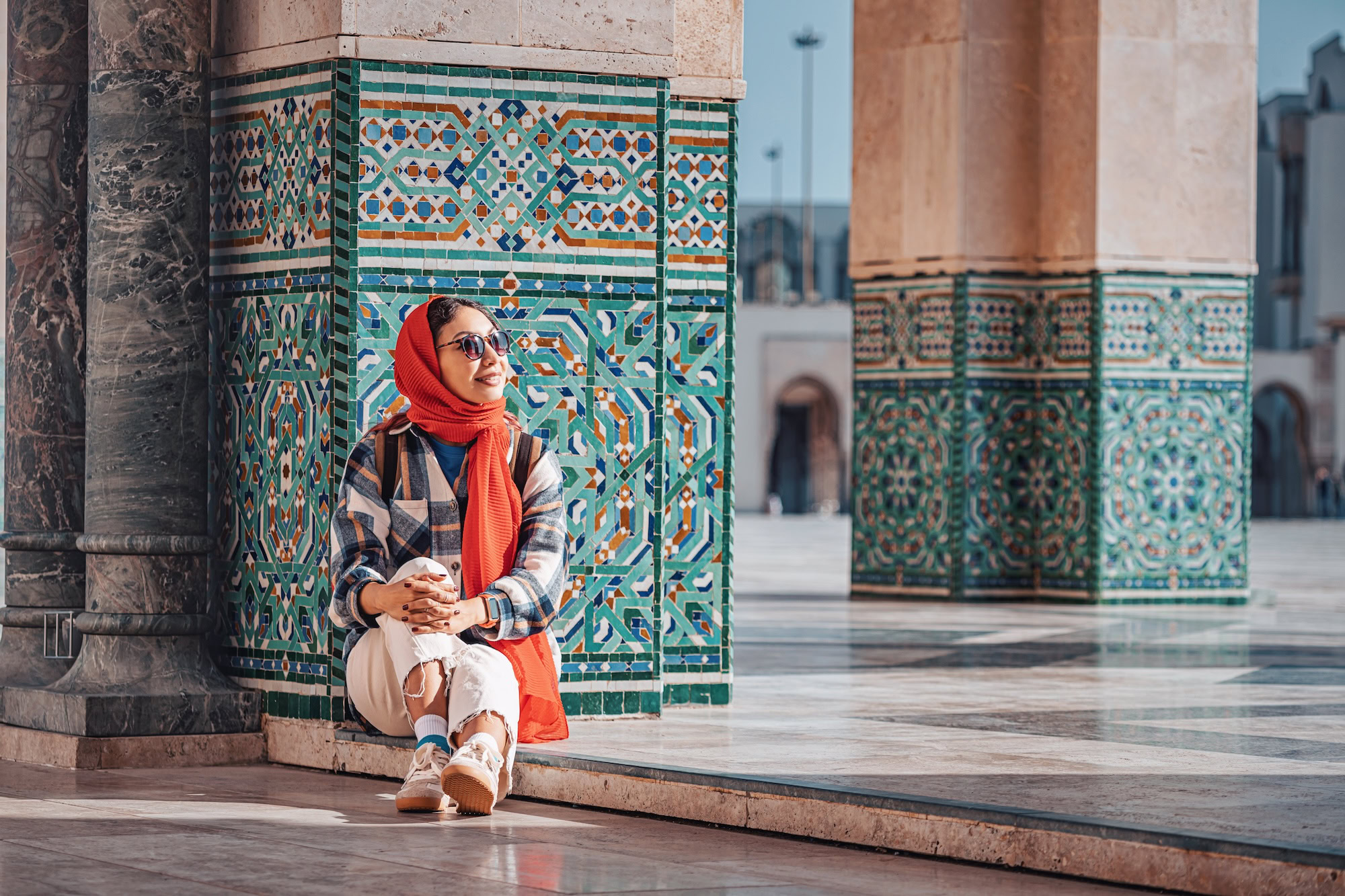 Mujer con hijab admirando los intrincados mosaicos geométricos y azulejos ornamentados de la arquitectura marroquí