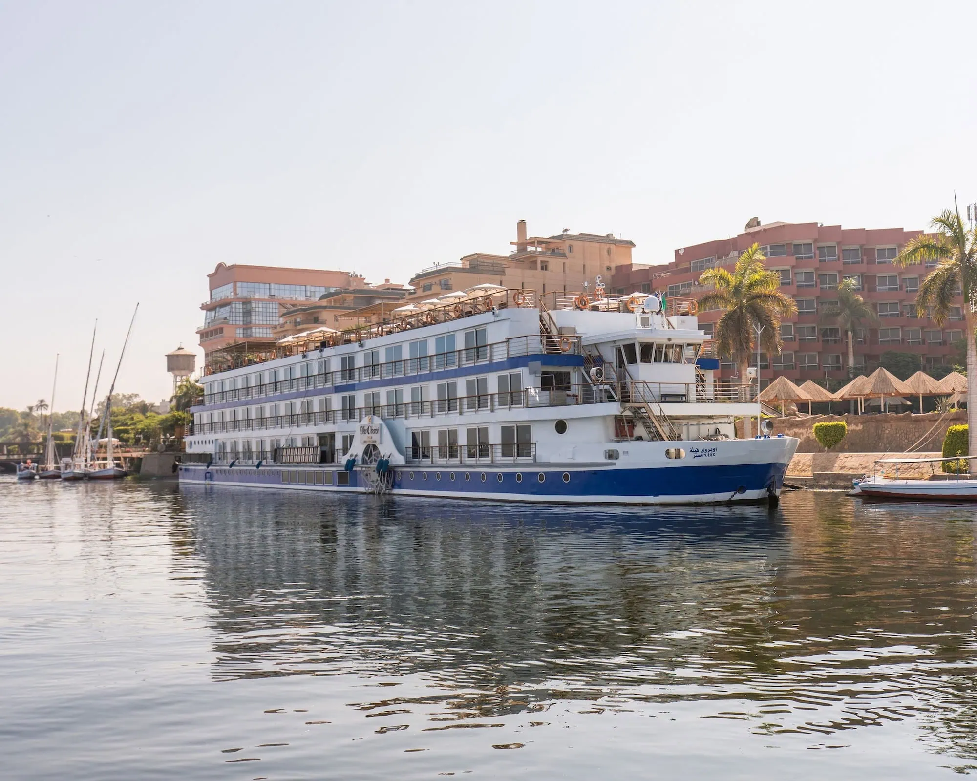 Nile River cruise ship docked along the riverbank with shoreline buildings visible, Luxor