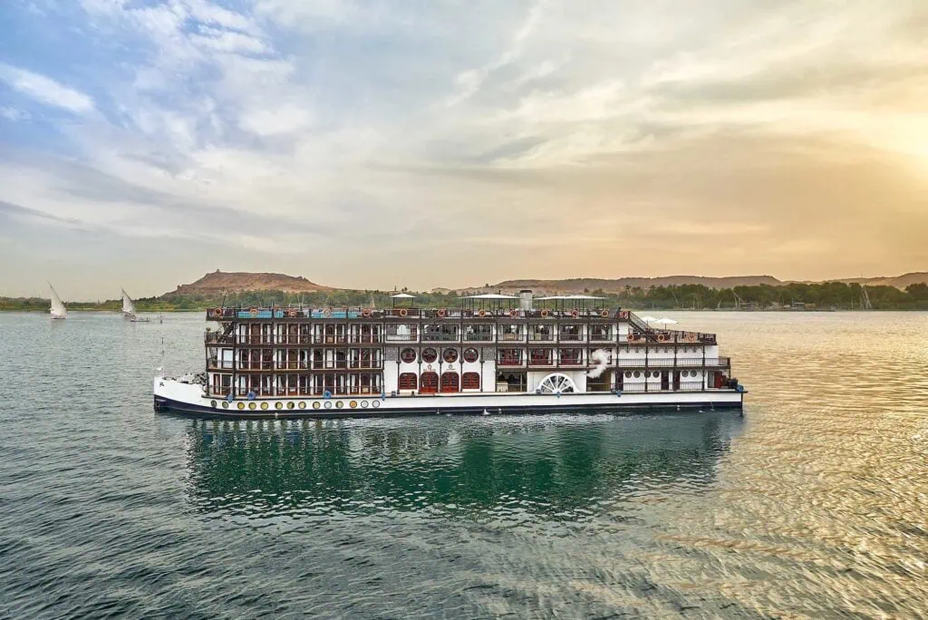 The historic SS Misr Nile cruise vessel sailing down the Nile River, with desert mountains rising in the background, Egypt.