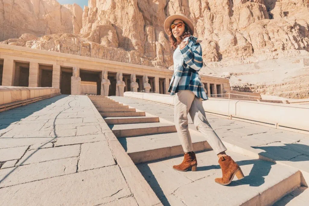 Woman traveler walking among the stone terraces and columns of the Temple of Hatshepsut