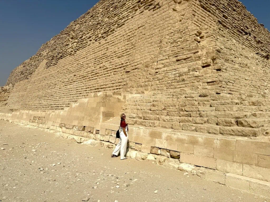 Tourist walking along the stone base of the Step Pyramid of Djoser at the Saqqara Necropolis, Saqqara