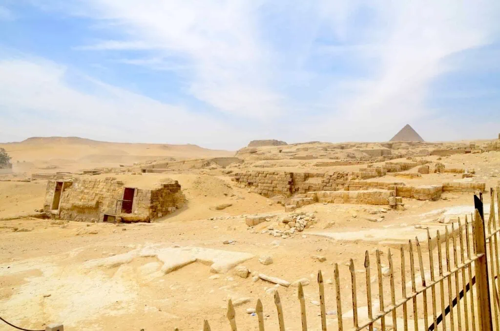 Mudbrick tombs and ongoing excavation areas at the Cemetery of the Pyramid Workers near the Giza plateau, photographed in golden afternoon light