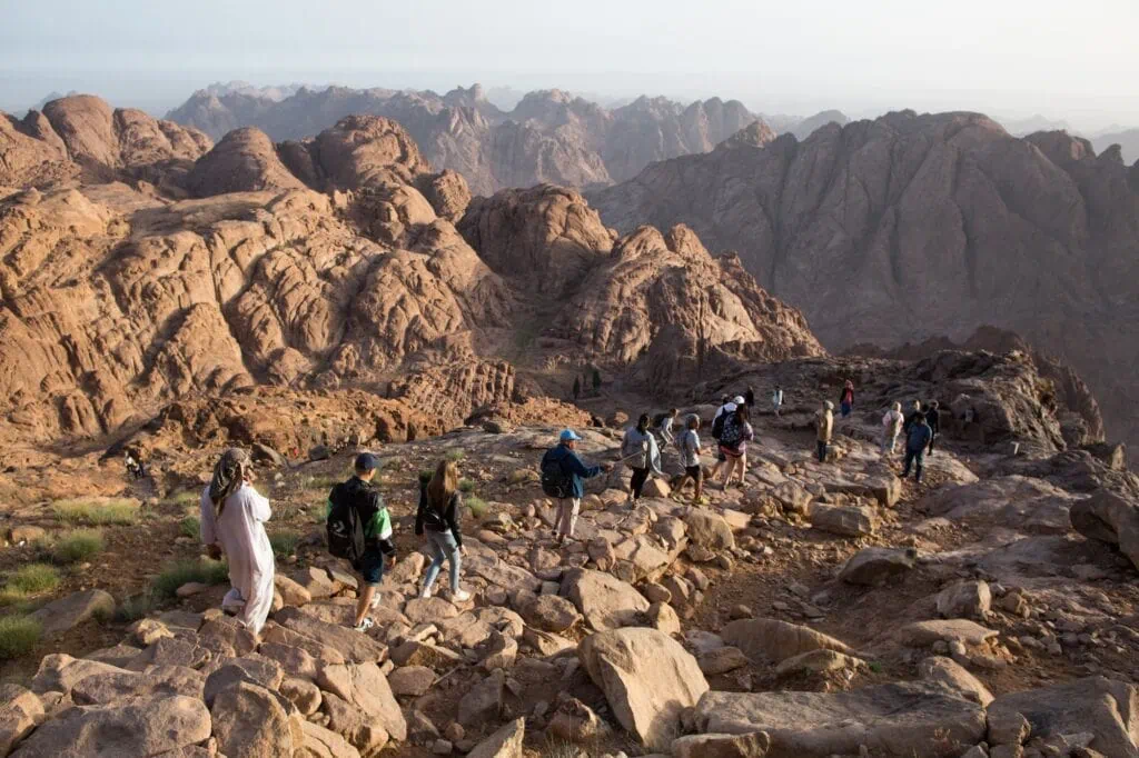 Mount Sinai showing tourists walking along a rocky mountain trail at sunrise with surrounding granite peaks, Saint Catherine