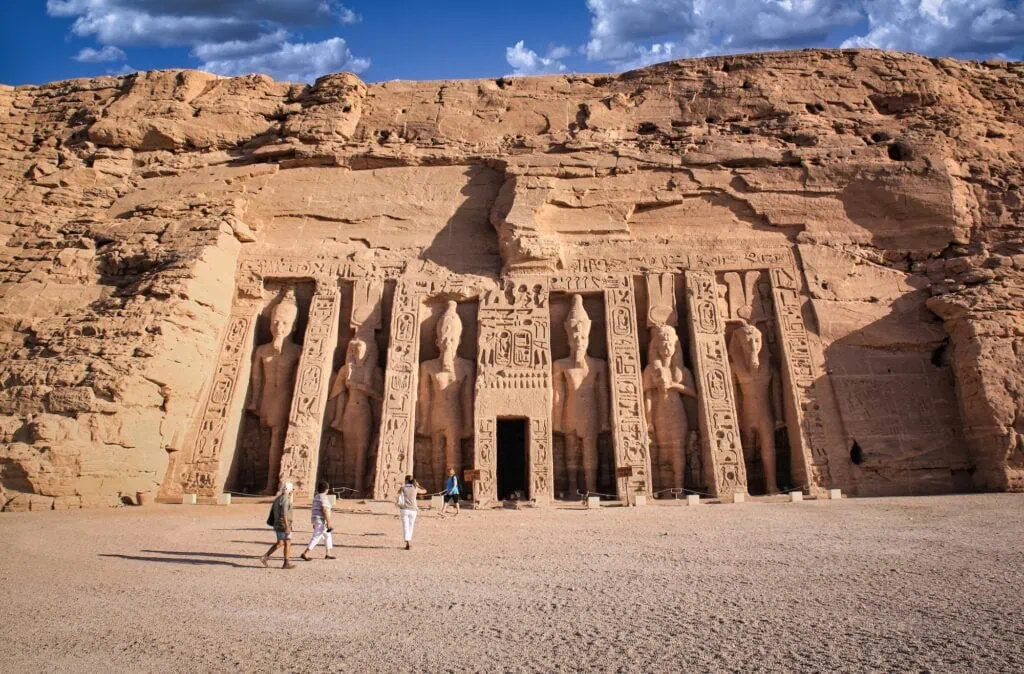 Six rock-cut 10 m colossi at the entrance to the Small Temple of Hathor and Nefertari at Abu Simbel — four representing Ramses II and two representing Queen Nefertari at equal size — only the second queen-dedicated temple in pharaonic Egyptian history, reachable by flight, road convoy, or Lake Nasser cruise extension from Aswan