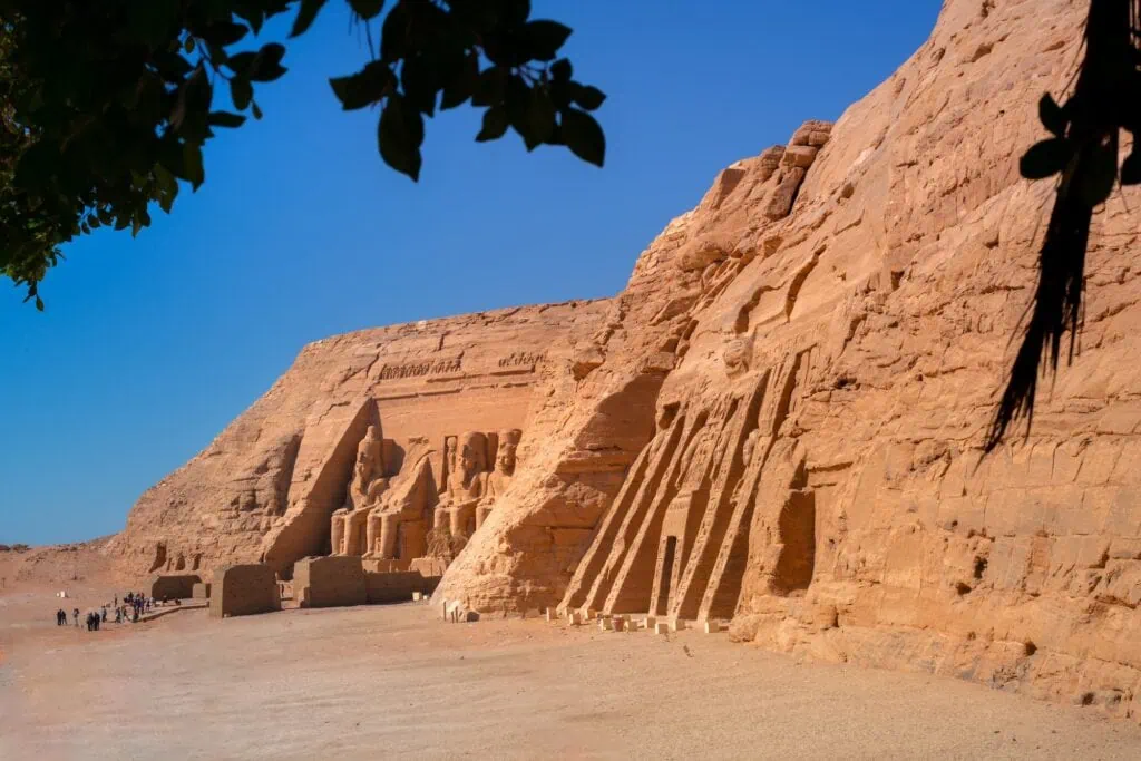 Wide view of Abu Simbel showing the seated colossi of the Great Temple of Ramses II in the middle distance and the rock-cut façade of the Small Temple of Hathor and Nefertari in the foreground, both relocated 65 m above the original site by UNESCO between 1964 and 1968.