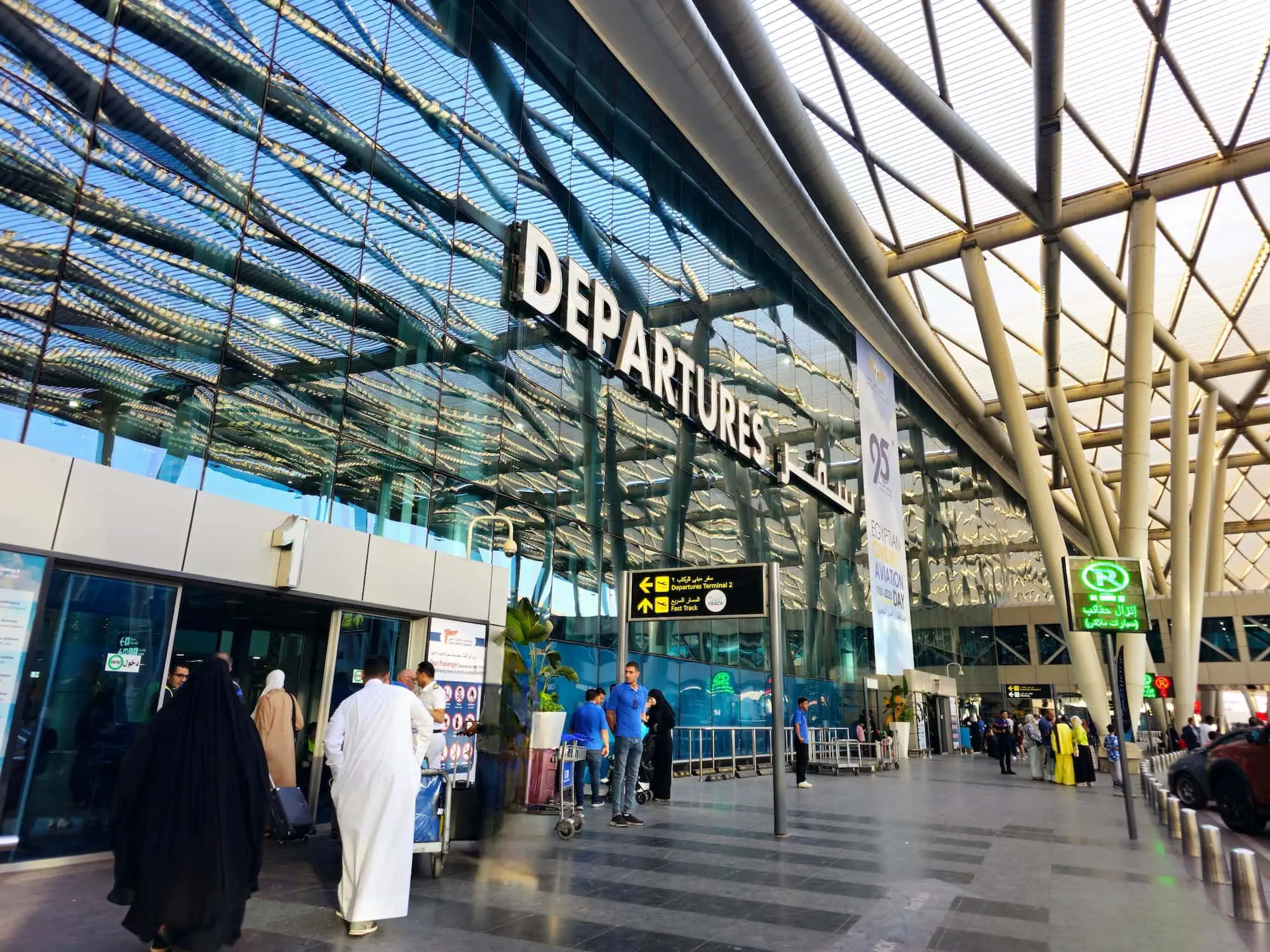 The modern entrance of Cairo International Airport with travellers outside the terminal, the arrival point for one-stop flights from Singapore via Doha, Dubai, Abu Dhabi, or Istanbul. Egypt tours from Singapore.