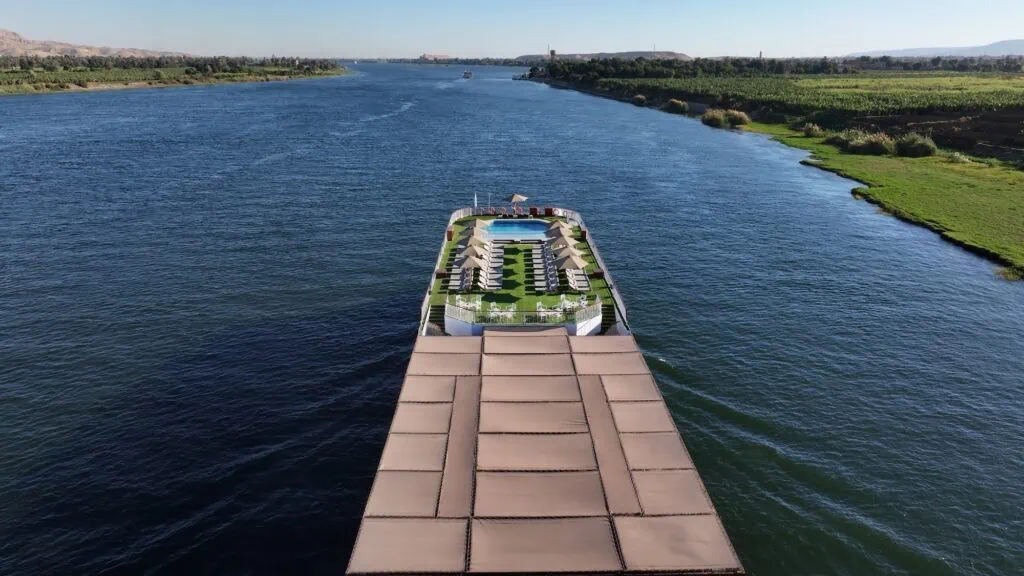 erial view of a multi-deck Luxury Nile Cruise vessel with rooftop pool sailing the Nile River between Luxor and Aswan, Egypt — 5-star vessel with panoramic cabins, sailing the standard 4-day Luxor–Aswan route