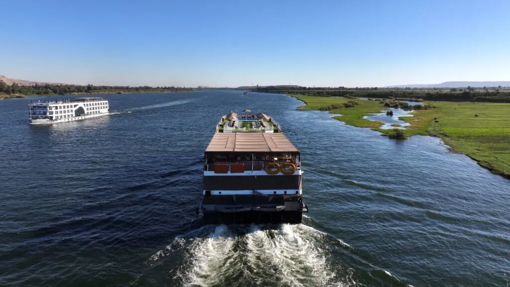 Multi-deck Luxury Nile Cruise vessels sailing on the Nile near Aswan with palm-fringed riverbanks