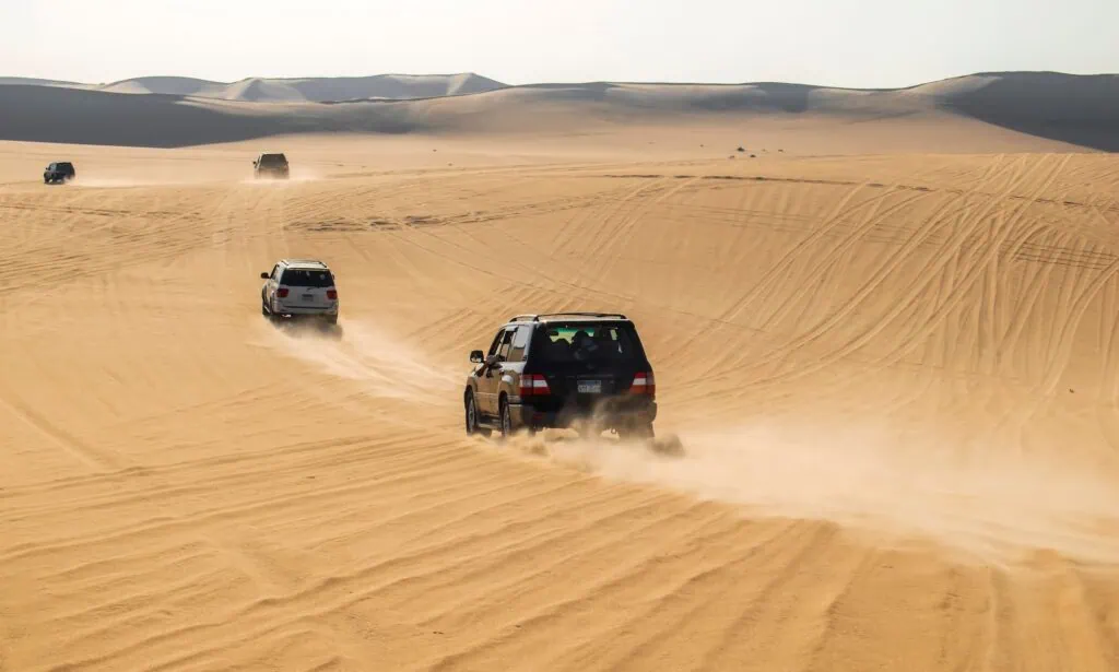 Safari vehicles driving across sand dunes in Siwa Desert Siwa