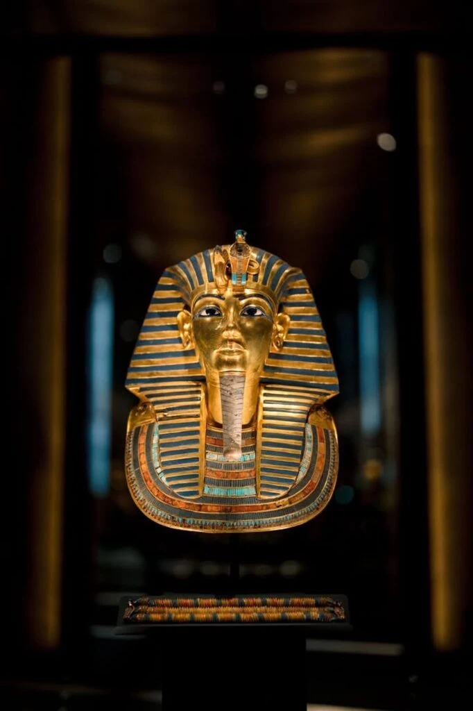 Close-up view of the golden funerary mask of King Tutankhamun on display at the Grand Egyptian Museum in Giza, Egypt — the 18th-dynasty boy king's death mask, made of solid 22-carat gold, dating to around 1323 BC - Middle East Vacations and Tours
