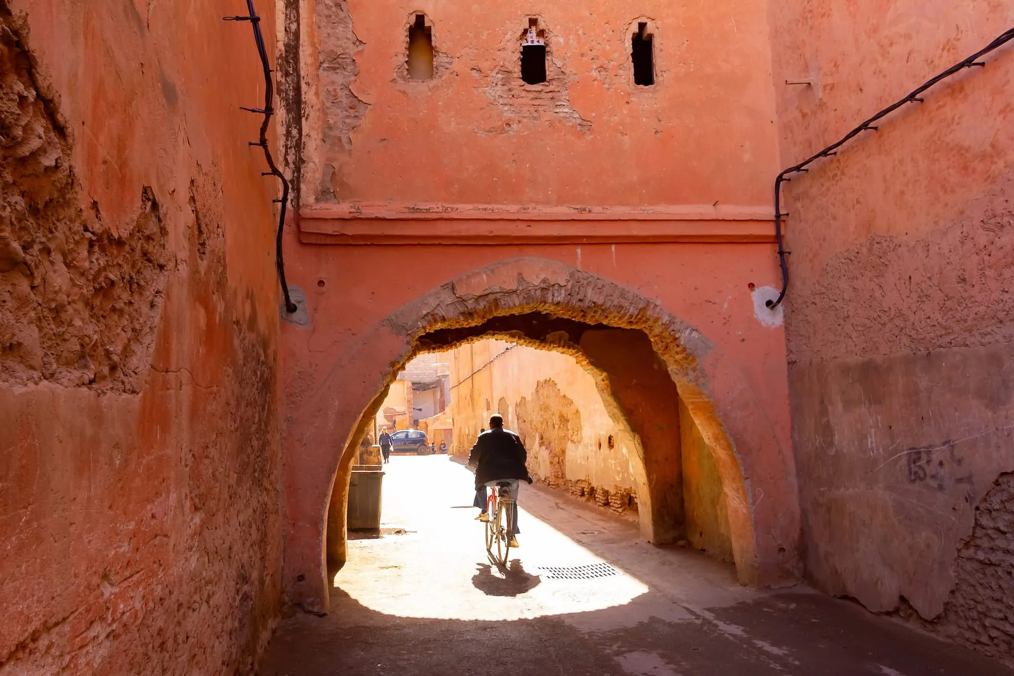 Narrow street in Marrakech medina with traditional red clay walls and arched passage