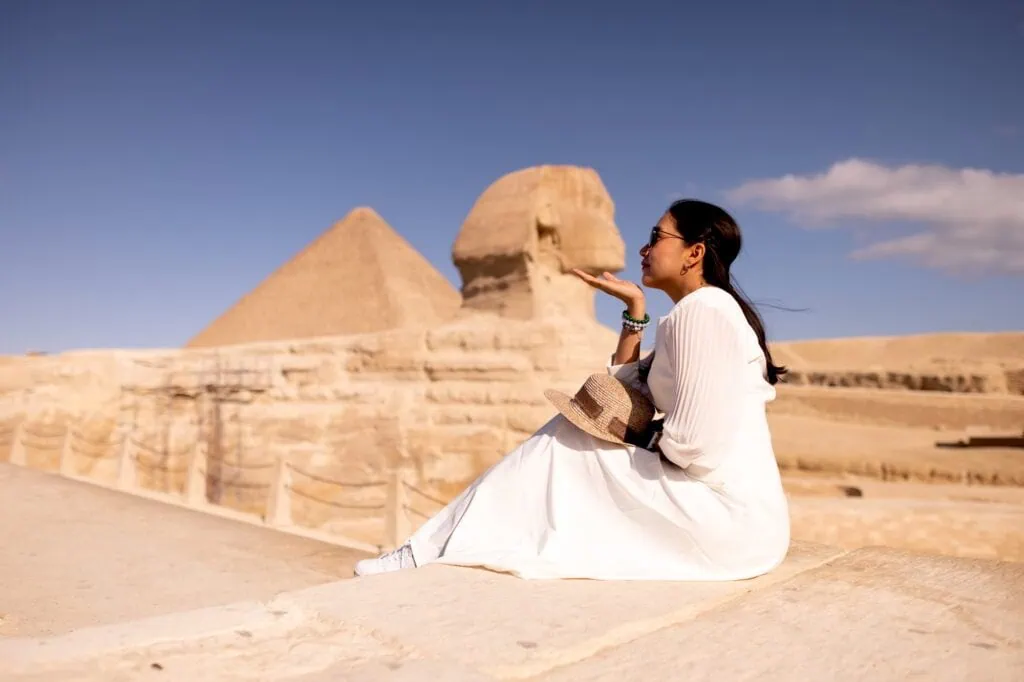 Visitor posing with the Great Sphinx of Giza, the limestone monument carved around 2,500 BC and standing 73 metres long beside the Pyramid of Khafre.