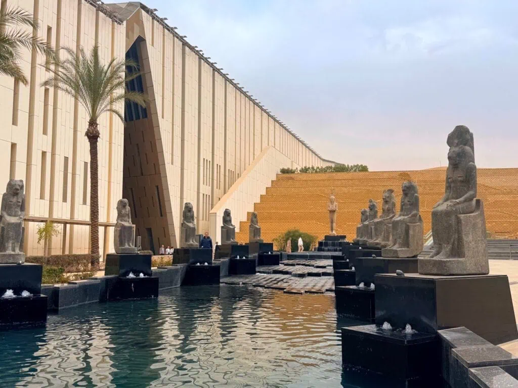 Terraced garden outside the Grand Egyptian Museum with monumental statues displayed along landscaped walkways, Giza