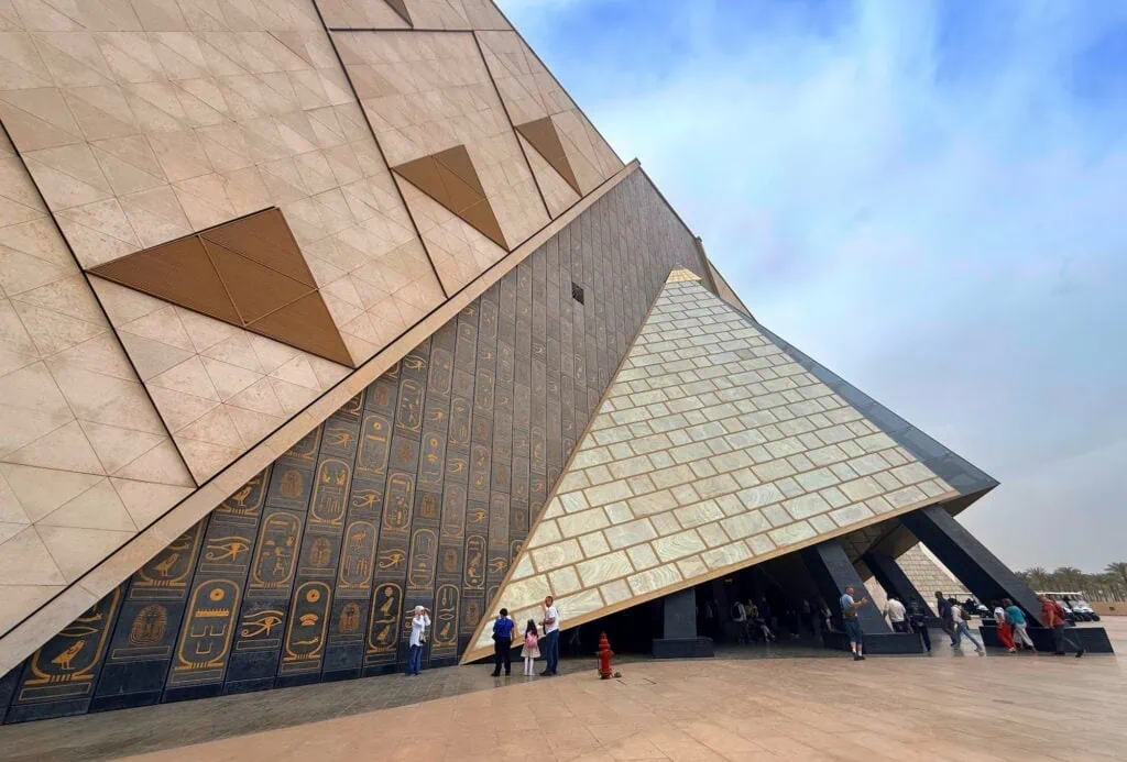 The monumental stone entrance facade of the Grand Egyptian Museum near the Giza plateau, with its distinctive triangular alabaster frontage, Egypt.