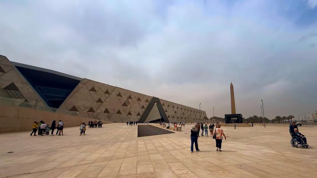 Exterior of the Grand Egyptian Museum near the Giza pyramids, its modern stone facade and open forecourt, a fully accessible, climate-controlled site well suited to senior travelers on a private Egypt tour. Egypt tours for seniors.