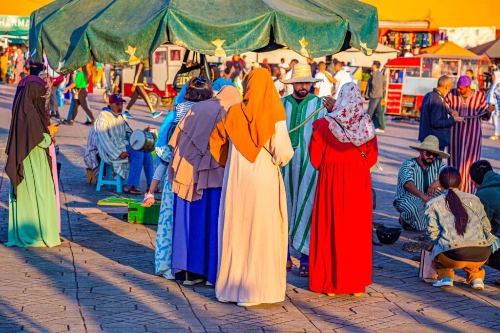 Jemaa el Fna square with women in traditional dress and a snake charmer performing, Marrakesh