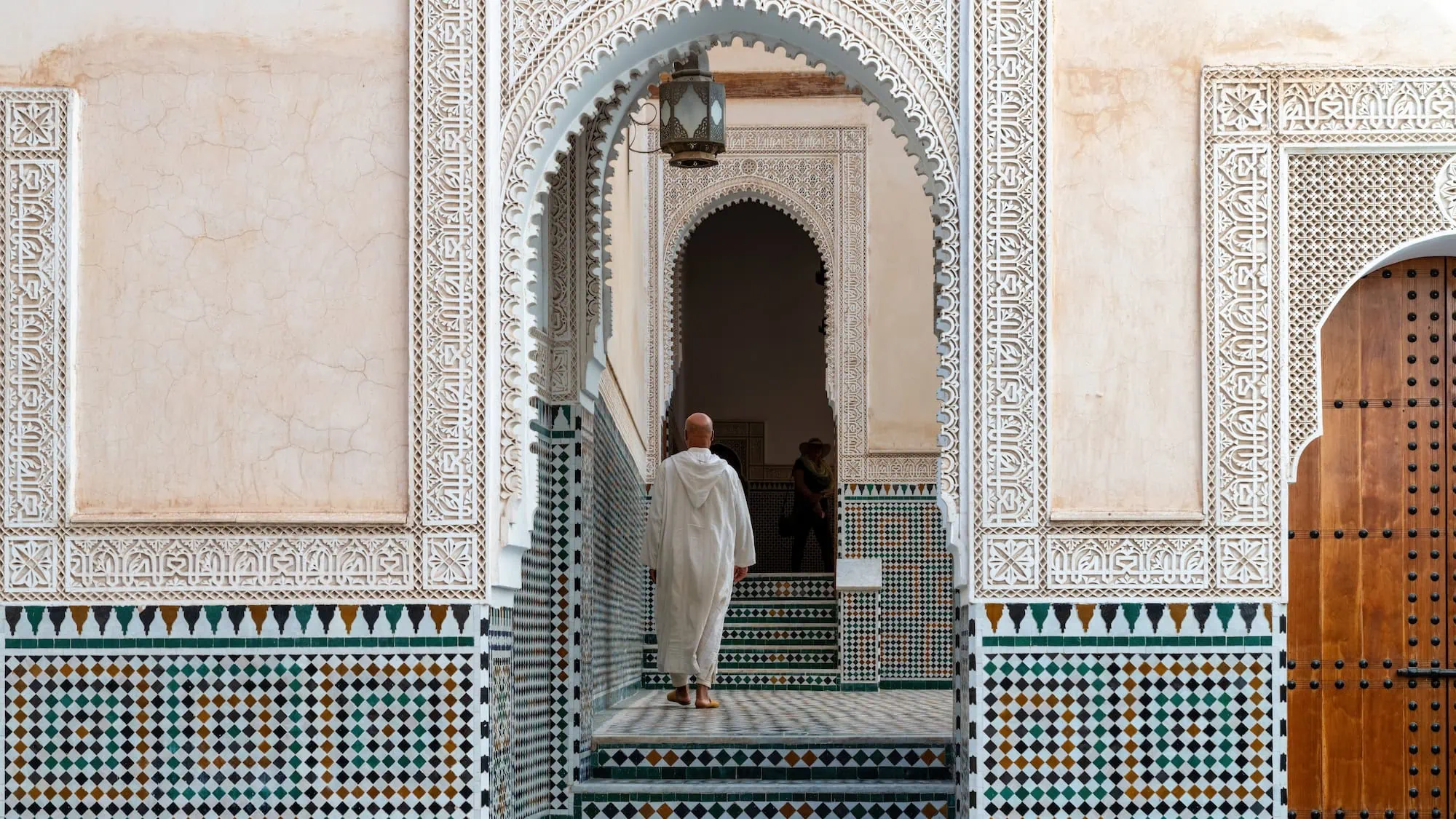 Man in traditional white robes walking through ornate interior of Moulay Ismail Mausoleum