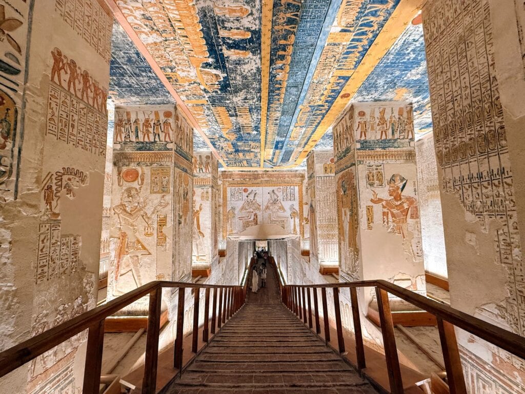 Decorated descending corridor of KV9, the Tomb of Ramesses V and Ramesses VI in the Valley of the Kings on Luxor's West Bank, with the elongated body of the sky goddess Nut painted across the vaulted ceiling depicting the Book of the Day and Book of the Night, and pillar reliefs showing Ramesses VI offering to Osiris and other deities.
