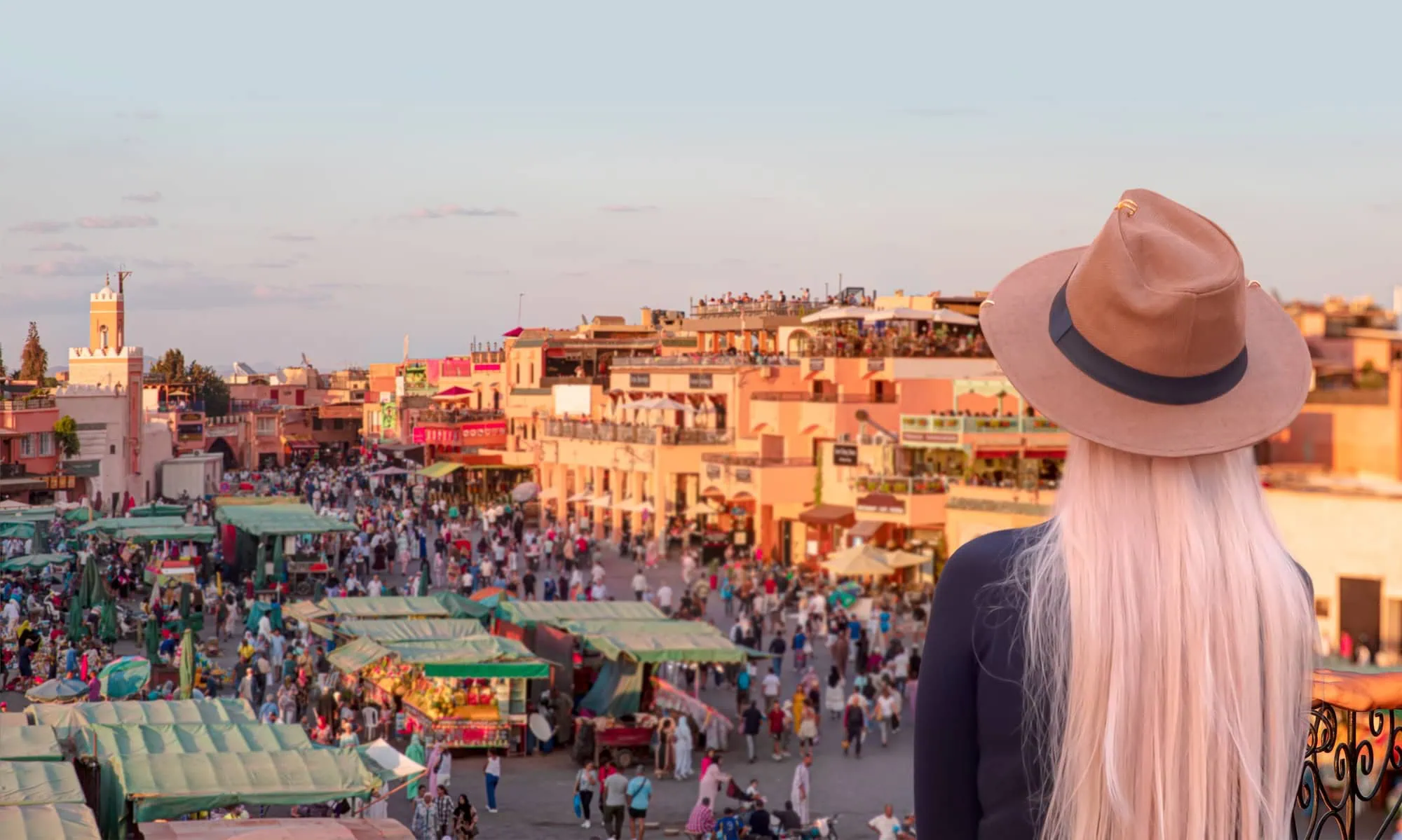 Woman overlooking bustling Jemaa el-Fnaa square in Marrakech during golden hour