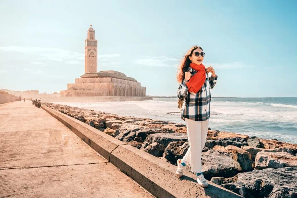 Person walking along the breakwater beside Hassan II Mosque with ocean views, Casablanca